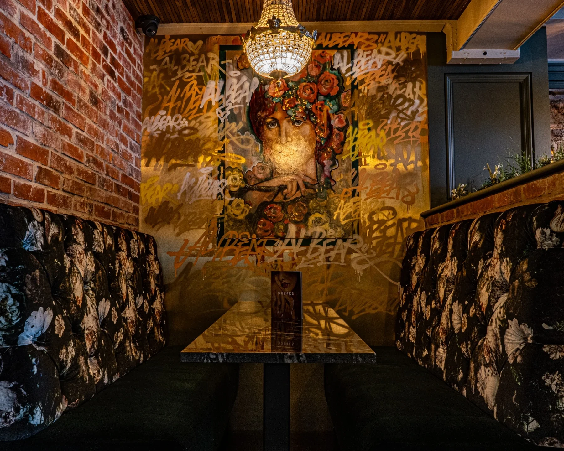 Al Bear booth seating beneath a chandelier and statement wall art